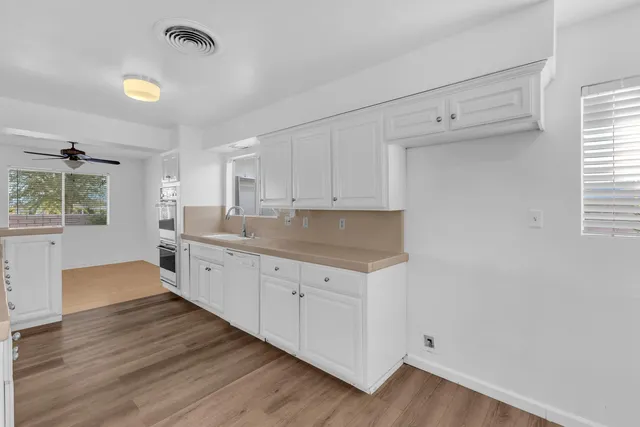 a large kitchen with a lot of counter space and wooden floor