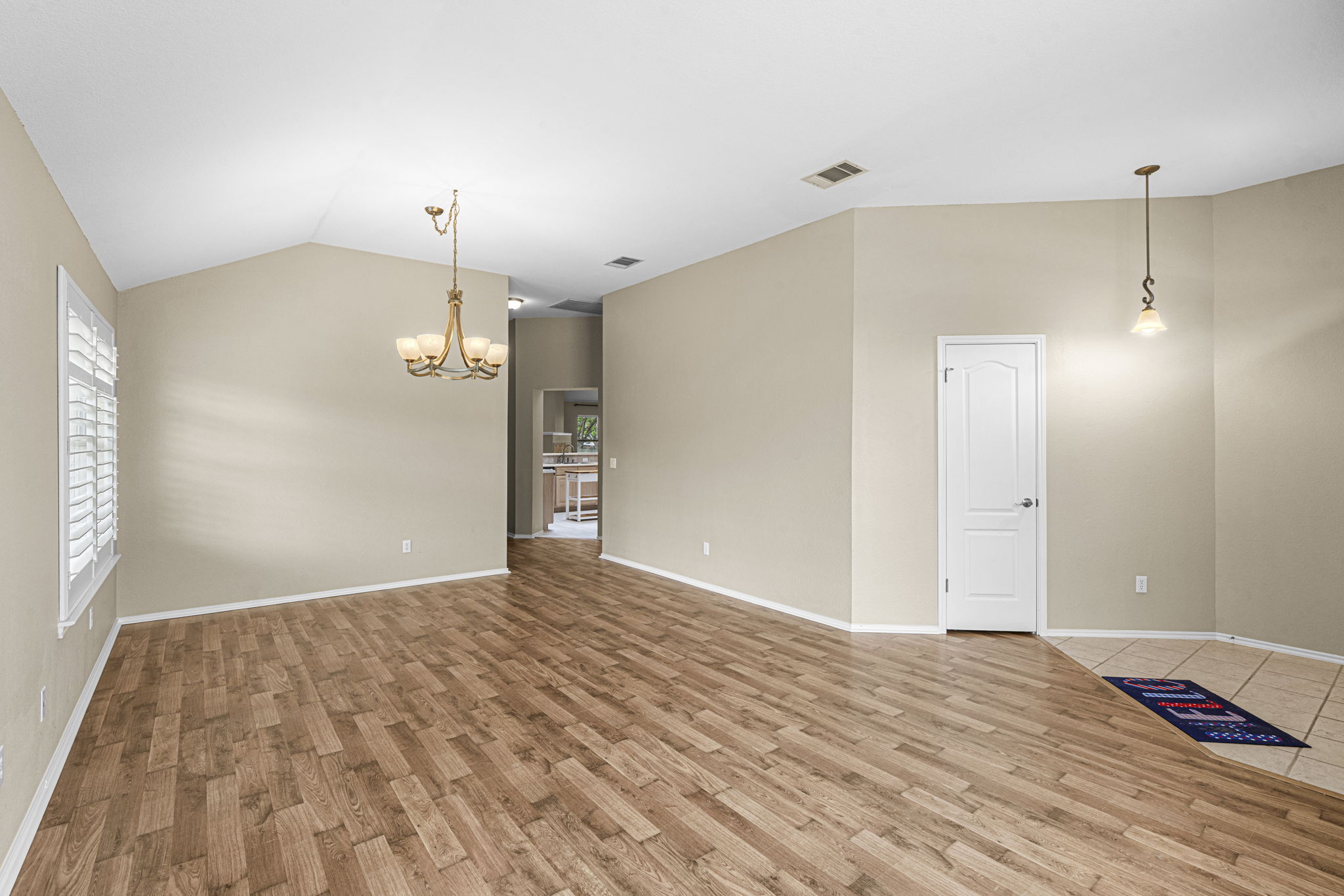7172 Ridge Oak Road Austin, TX 78749 - Photo 16 of 40 Natural light illuminates this spacious living area, featuring warm wood-look flooring and vaulted ceilings.