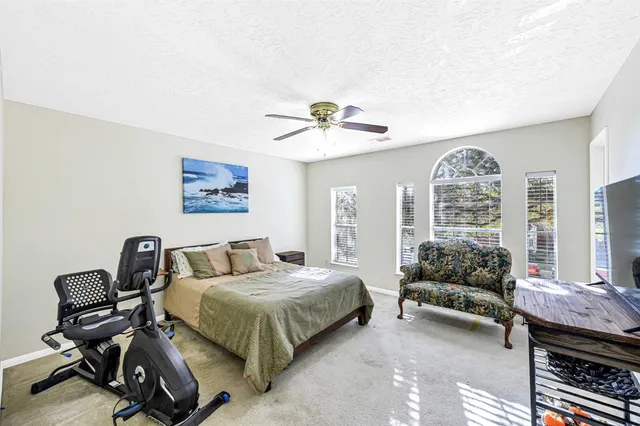 a bedroom with a bed gym equipment and a large window