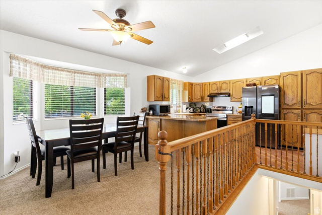 5321 South 3100th Street West Roy, UT 84067 - Photo 33 of 64 Open-concept kitchen and dining area featuring warm wood cabinetry, a central island with countertop seating, and a bay window