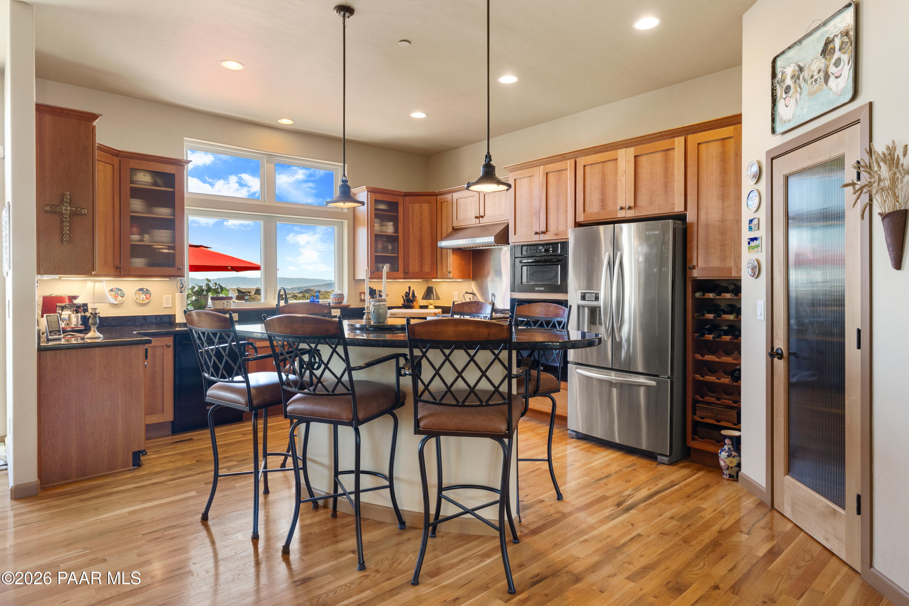 1448 Short Point Lane Prescott, AZ 86305 - Photo 22 of 56 a kitchen with stainless steel appliances kitchen island granite countertop a refrigerator a stove a sink a dining table and chairs with wooden floor