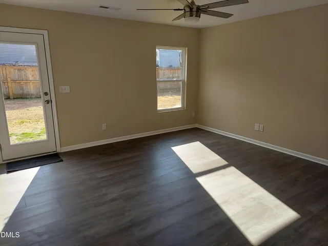 an empty room with wooden floor fan and windows