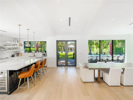 a kitchen with stainless steel appliances granite countertop a stove a refrigerator a kitchen island a dining table and chairs with wooden floor