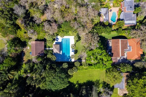 an aerial view of residential houses with outdoor space and trees