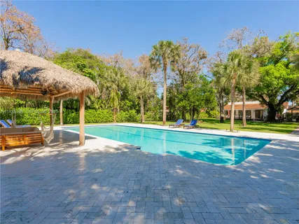 a view of swimming pool with large trees and lawn chairs