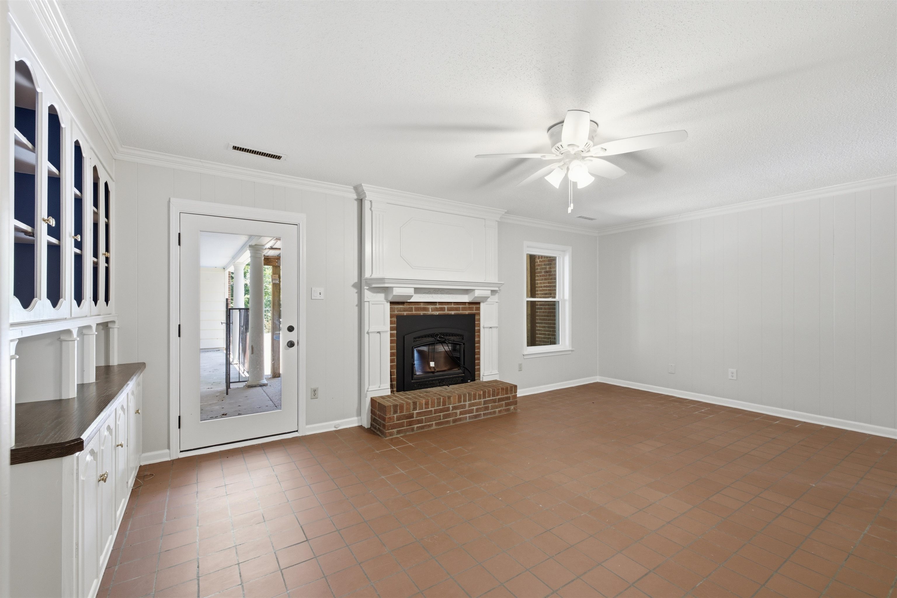 1370 North Reid Hooker Road Eads, TN 38028 - Photo 25 of 39 Living room with terracotta-style tile flooring, a brick fireplace with a white mantel, and built-in cabinetry with a dark wood-finish countertop