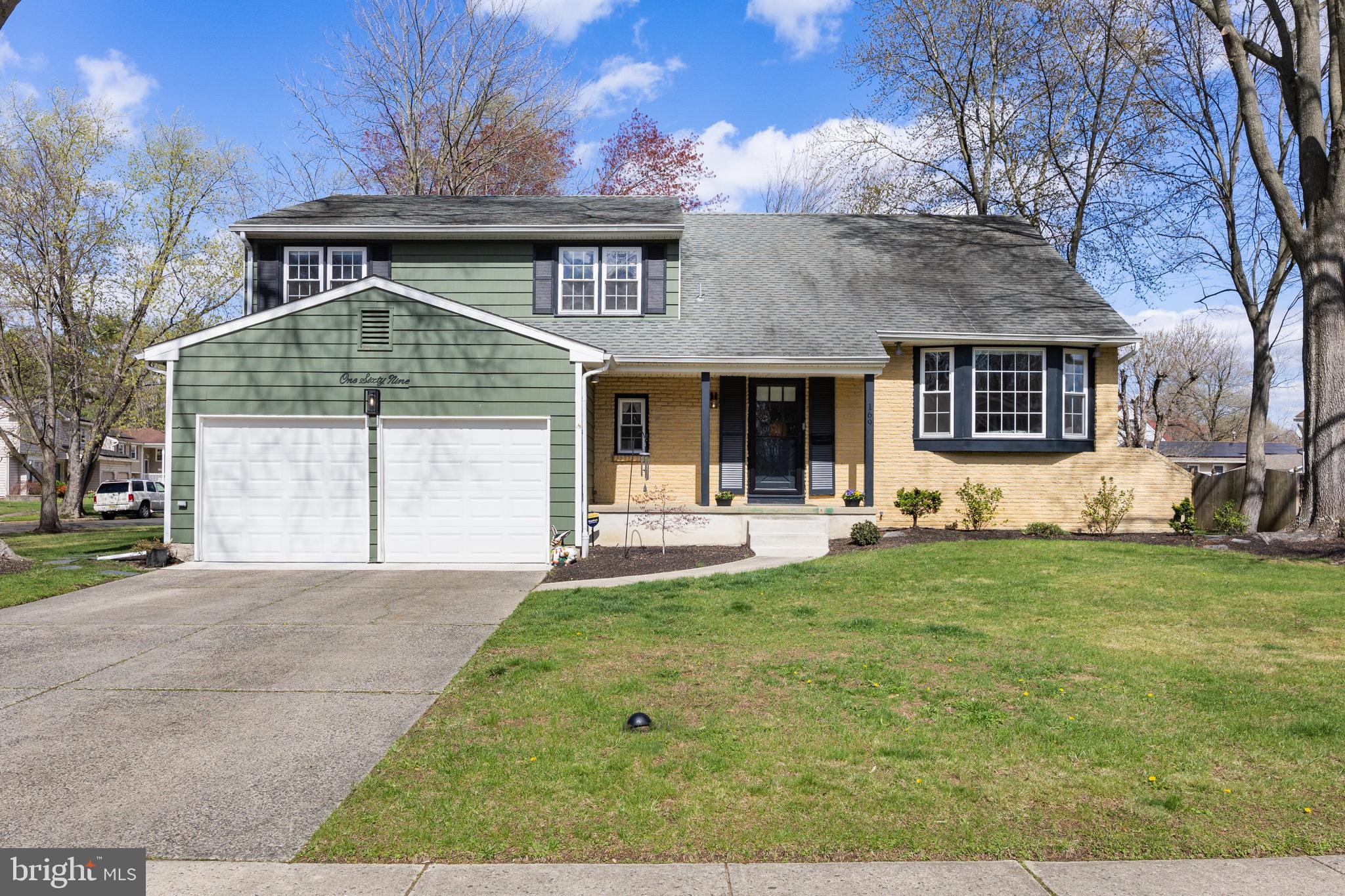 a front view of a house with a garden and trees