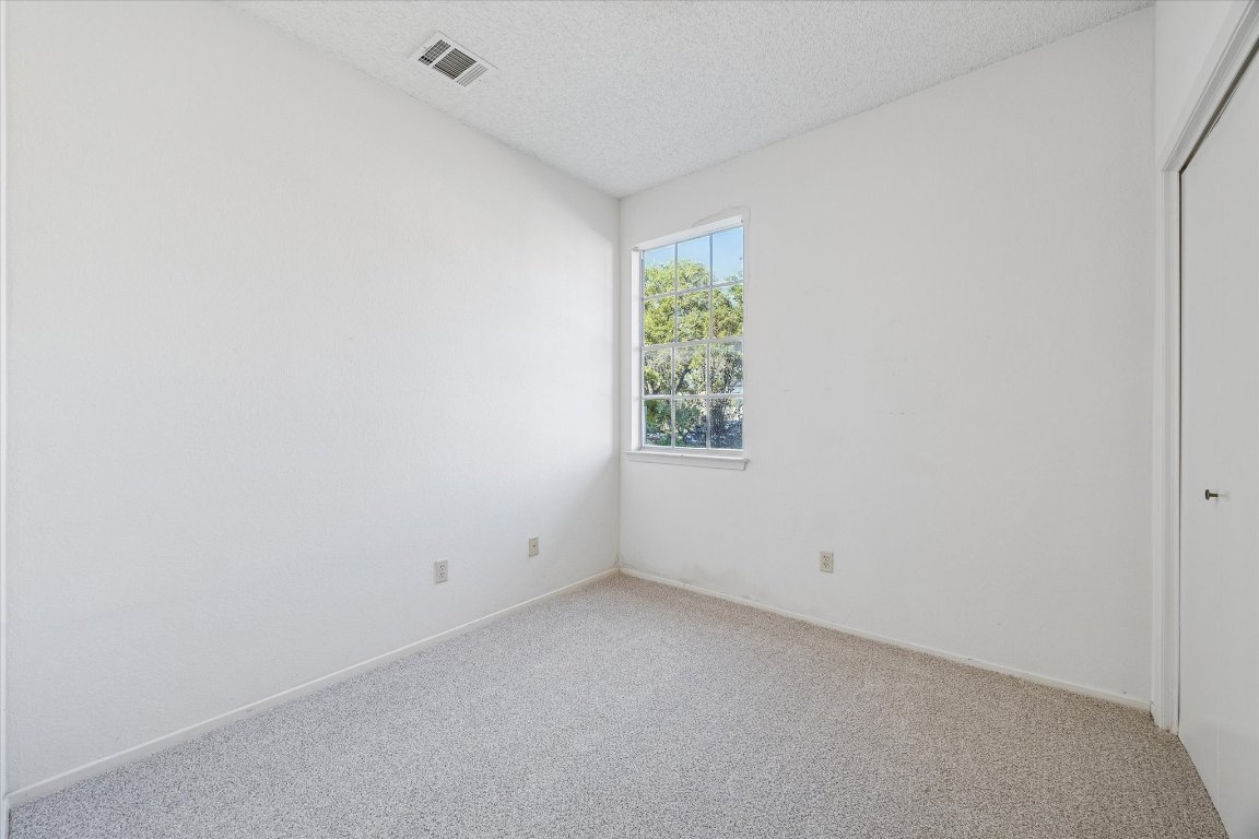6501 Brush Country Road, Unit 120 Austin, TX 78749 - Photo 19 of 35 Unfurnished bedroom featuring a closet, carpet flooring, and a textured ceiling