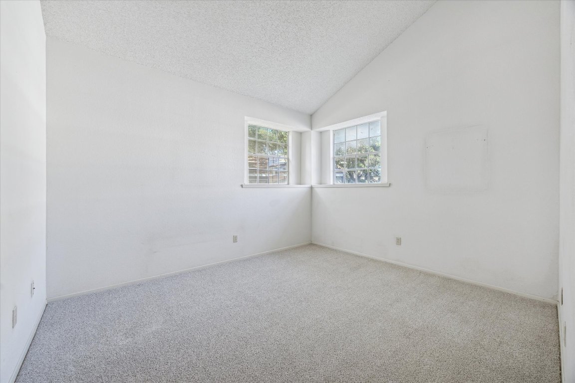 6501 Brush Country Road, Unit 120 Austin, TX 78749 - Photo 20 of 35 Empty room featuring vaulted ceiling, carpet, and a textured ceiling
