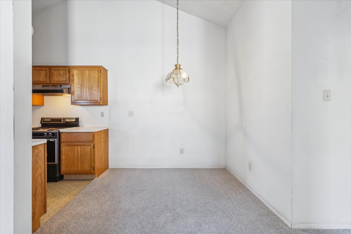 6501 Brush Country Road, Unit 120 Austin, TX 78749 - Photo 22 of 35 Kitchen featuring gas range, light countertops, pendant lighting, light carpet, and brown cabinets