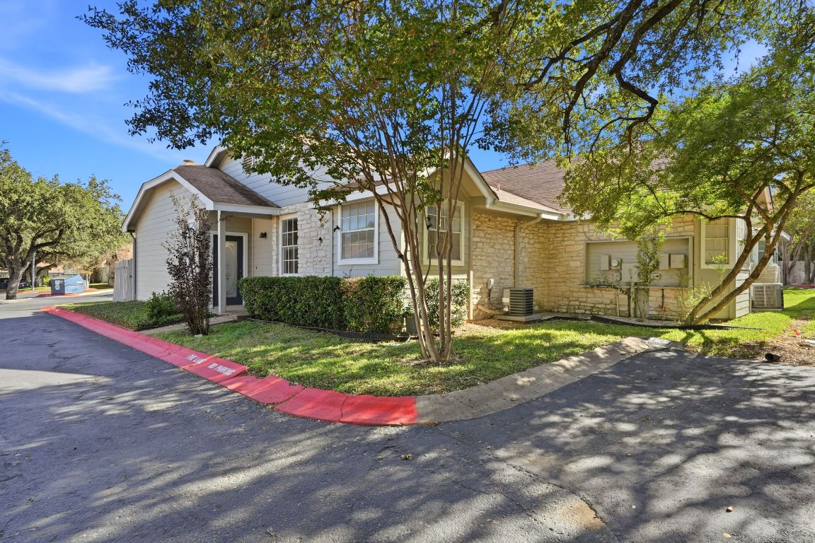 6501 Brush Country Road, Unit 120 Austin, TX 78749 - Photo 3 of 35 View of front of property featuring stone siding, a shingled roof, and a front lawn
