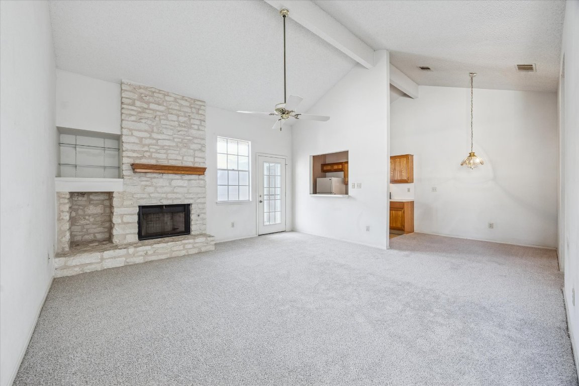 6501 Brush Country Road, Unit 120 Austin, TX 78749 - Photo 7 of 35 Unfurnished living room with beam ceiling, high vaulted ceiling, carpet floors, a fireplace, and ceiling fan