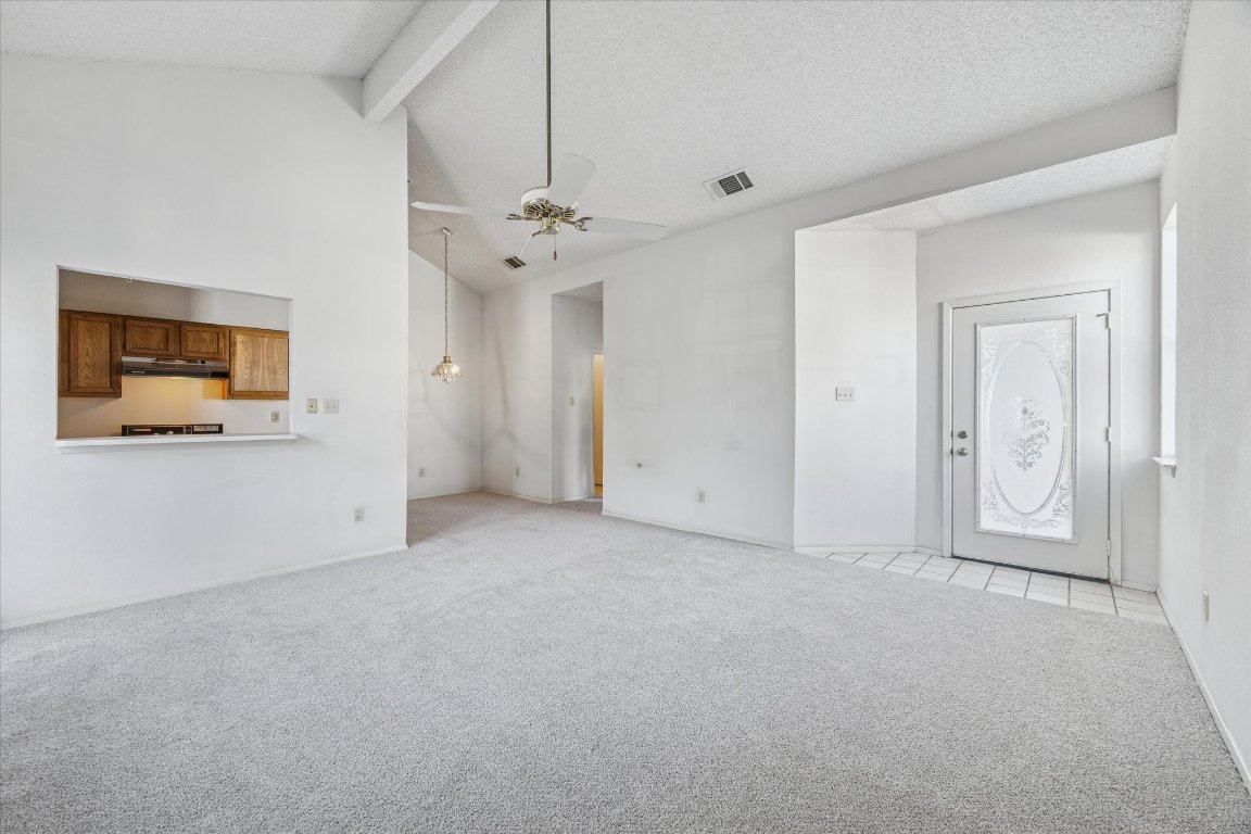 6501 Brush Country Road, Unit 120 Austin, TX 78749 - Photo 8 of 35 Unfurnished living room featuring carpet flooring, beamed ceiling, a ceiling fan, a textured ceiling, and high vaulted ceiling