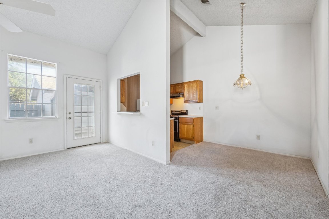 6501 Brush Country Road, Unit 120 Austin, TX 78749 - Photo 9 of 35 Unfurnished living room with high vaulted ceiling, light colored carpet, ceiling fan, beam ceiling, and a textured ceiling