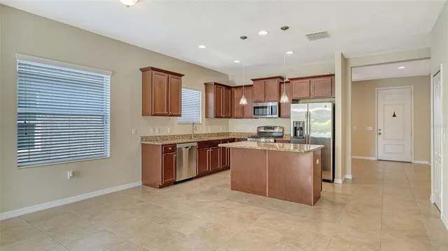 a kitchen with kitchen island granite countertop a sink window and stainless steel appliances