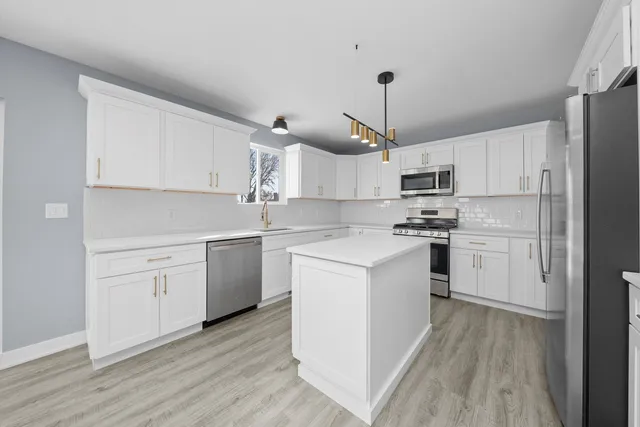 a kitchen with white cabinets stainless steel appliances and a window