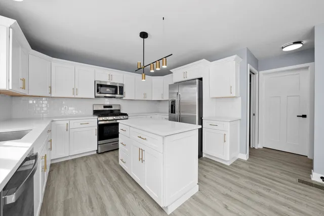 a kitchen with stainless steel appliances a refrigerator a stove a sink and white cabinets