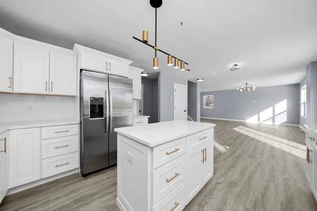 a kitchen with a refrigerator and countertop white cabinets