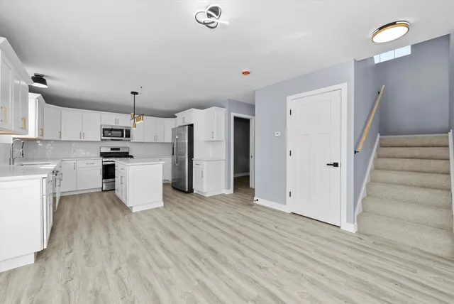a large white kitchen with white cabinets and stainless steel appliances