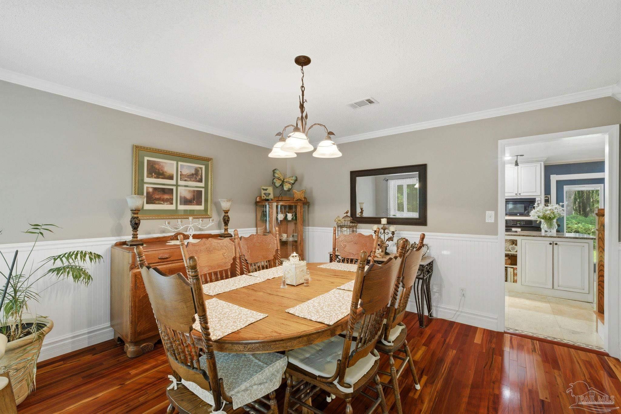 6930 Summit Way Milton, FL 32570 - Photo 15 of 71 a dining room with furniture a chandelier and wooden floor