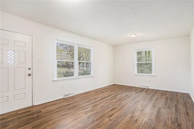 a view of an empty room with wooden floor and a window