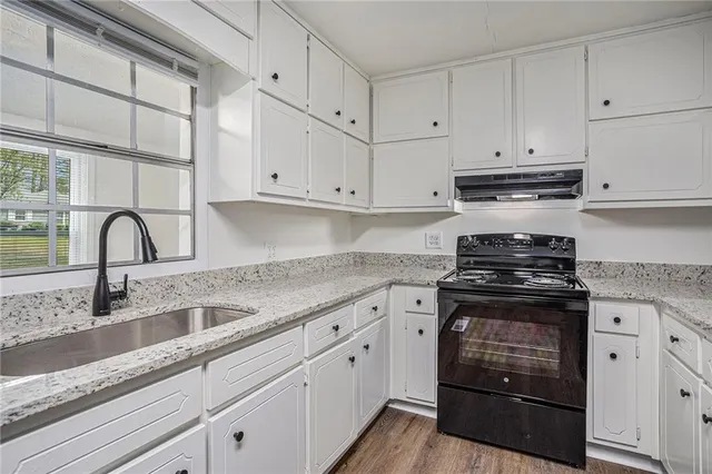 a kitchen with granite countertop white cabinets and stainless steel appliances
