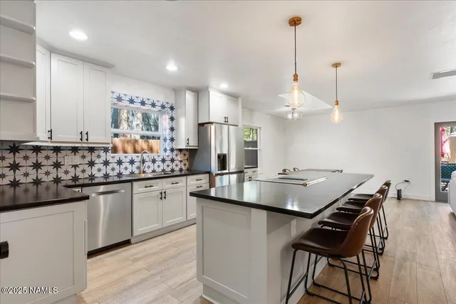 a kitchen with kitchen island granite countertop a sink a counter space appliances and cabinets
