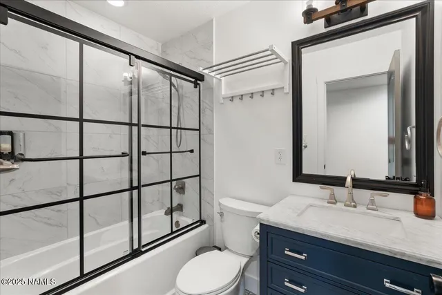 a bathroom with a granite countertop sink toilet mirror and a shower