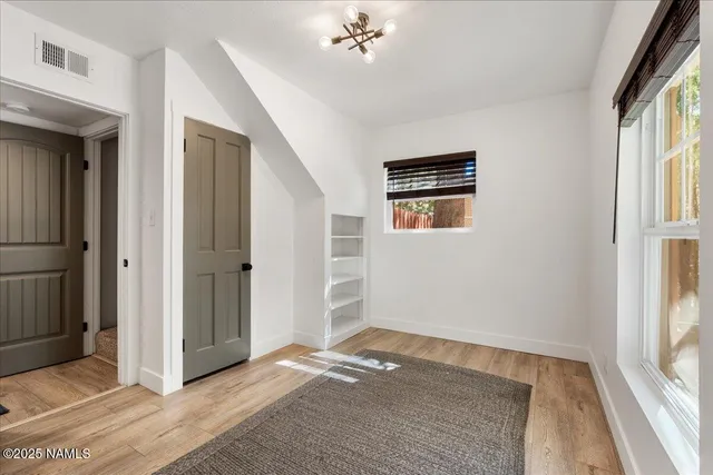 a view of an empty room with a window and wooden floor