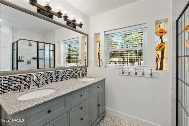 a bathroom with a granite countertop double vanity sink and mirror with large window