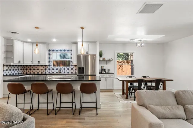 a kitchen with stainless steel appliances kitchen island granite countertop a dining table chairs and a refrigerator