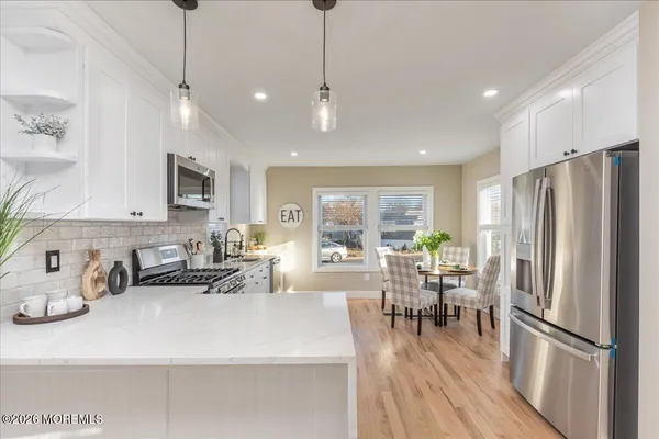 a kitchen with stainless steel appliances a dining table chairs refrigerator and cabinets