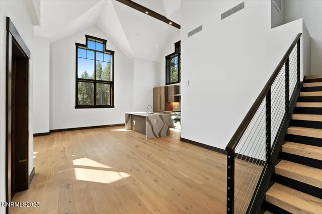 a view of an empty room with wooden floor and furniture