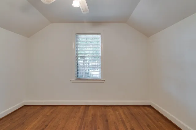 an empty room with wooden floor cabinet and windows