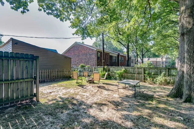a view of backyard with wooden fence and a large tree