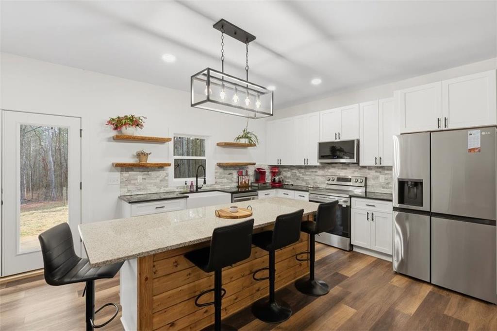 1475 Ben Davis Road Buchanan, GA 30113 - Photo 12 of 61 a kitchen with stainless steel appliances a dining table chairs refrigerator and microwave