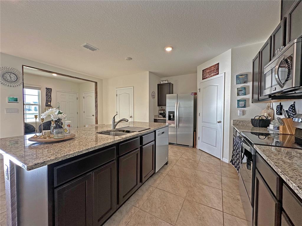 6988 Botanic Boulevard Harmony, FL 34773 - Photo 11 of 61 a kitchen with stainless steel appliances granite countertop a sink stove and refrigerator