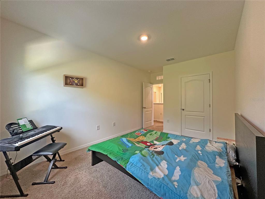 6988 Botanic Boulevard Harmony, FL 34773 - Photo 28 of 61 a bedroom with a bed and a table in it
