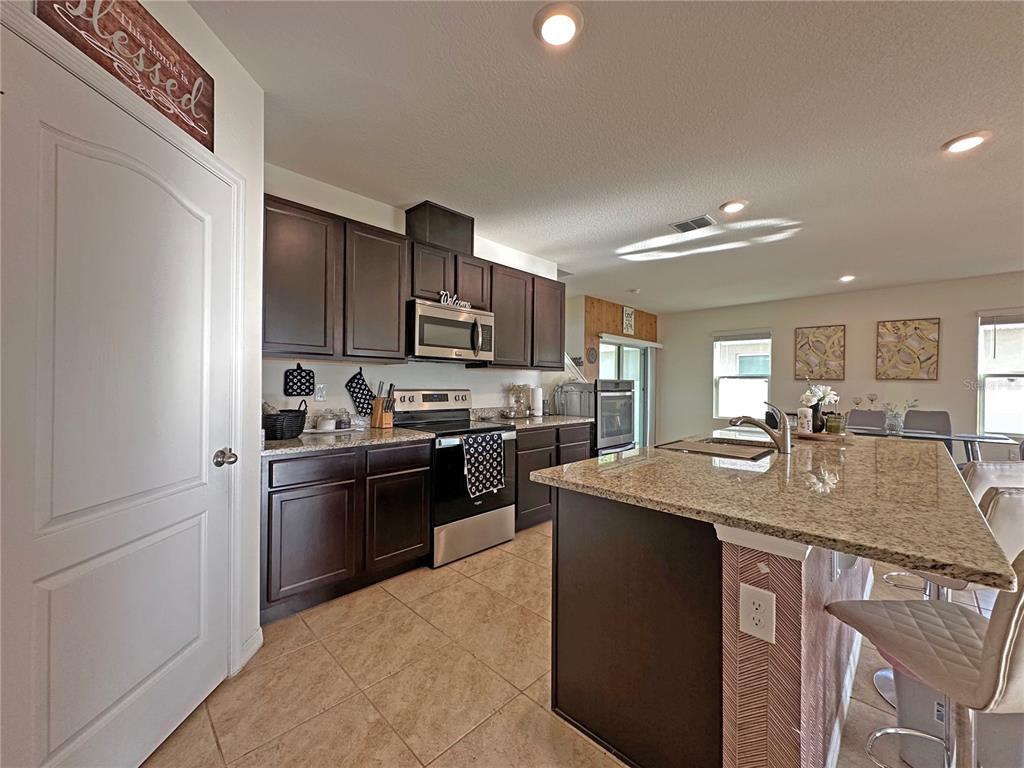 6988 Botanic Boulevard Harmony, FL 34773 - Photo 9 of 61 a kitchen with stainless steel appliances granite countertop a sink stove and refrigerator