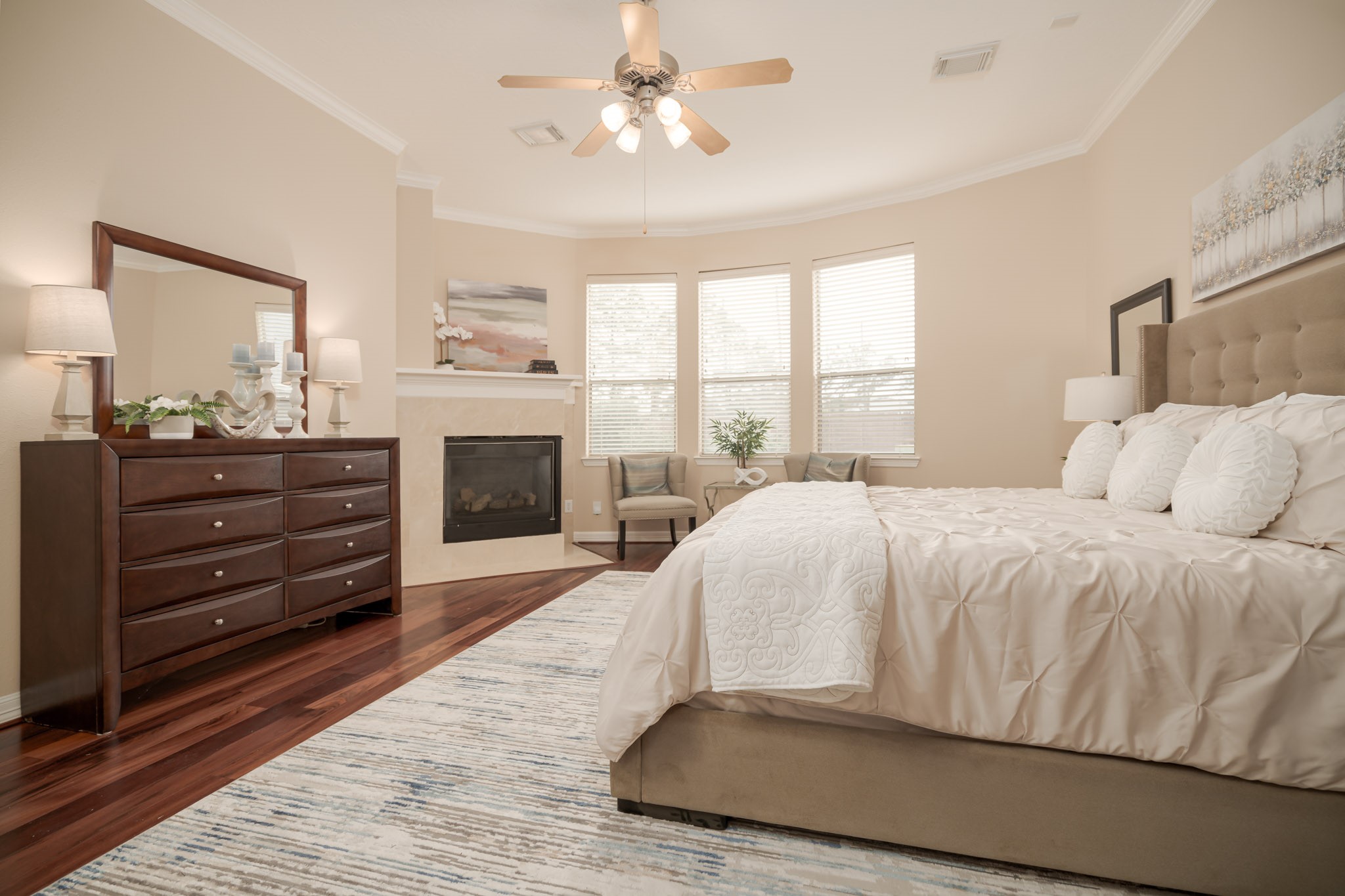 6506 Monte Bello Ridge Lane Houston, TX 77041 - Photo 8 of 39 Discover the inviting primary bedroom downstairs, featuring elegant hardwood floors, a cozy fireplace, and abundant natural light from expansive windows—perfect for your serene retreat.