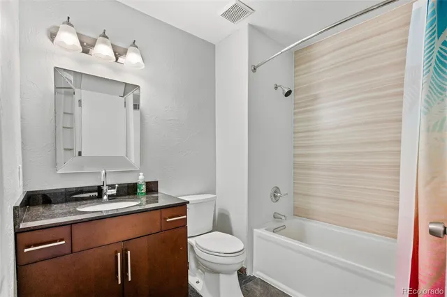 a bathroom with a granite countertop sink toilet and shower