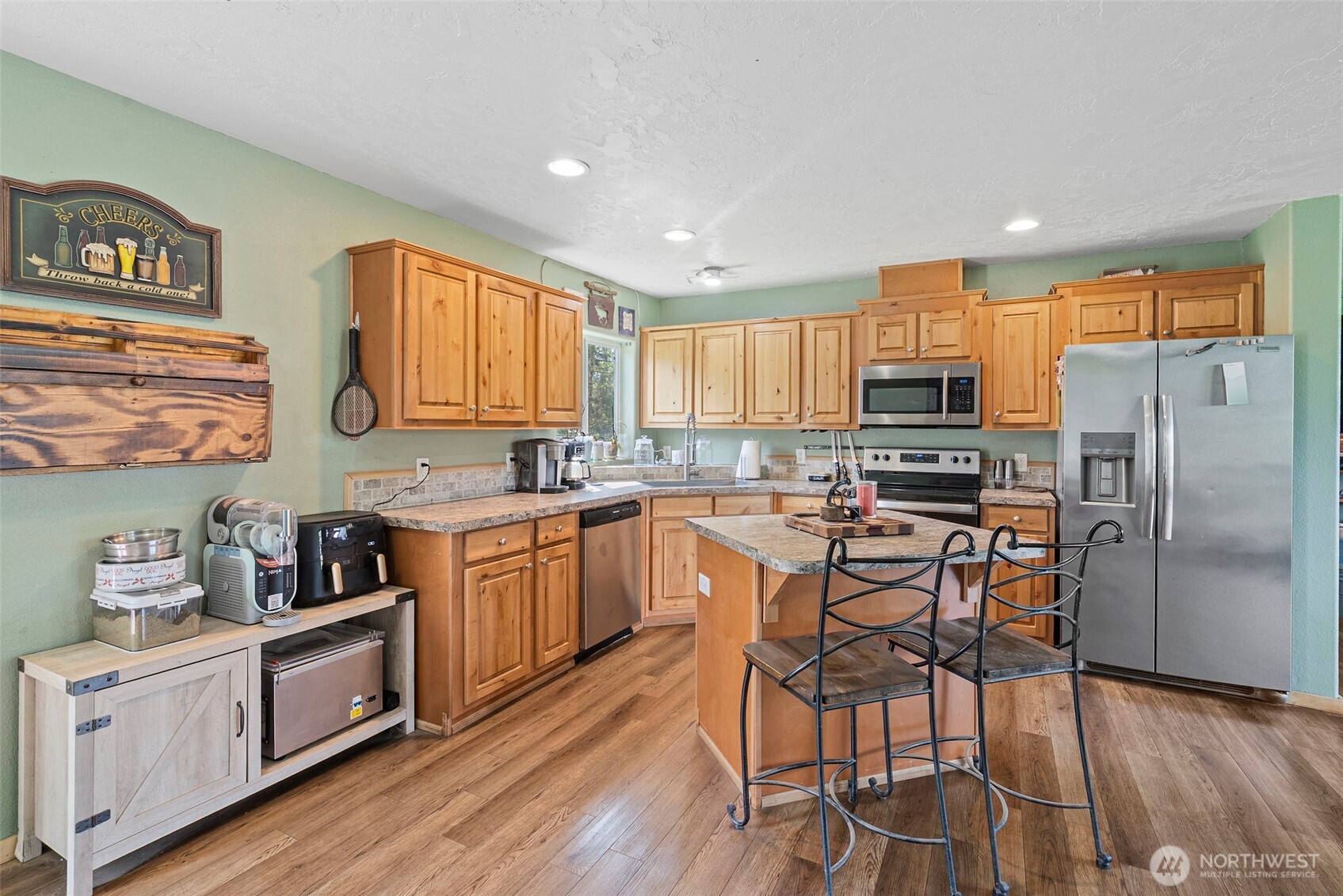 291 East Orchid Lane Grapeview, WA 98546 - Photo 7 of 37 a kitchen with stainless steel appliances a microwave a stove a sink dishwasher a refrigerator and cabinets with wooden floor