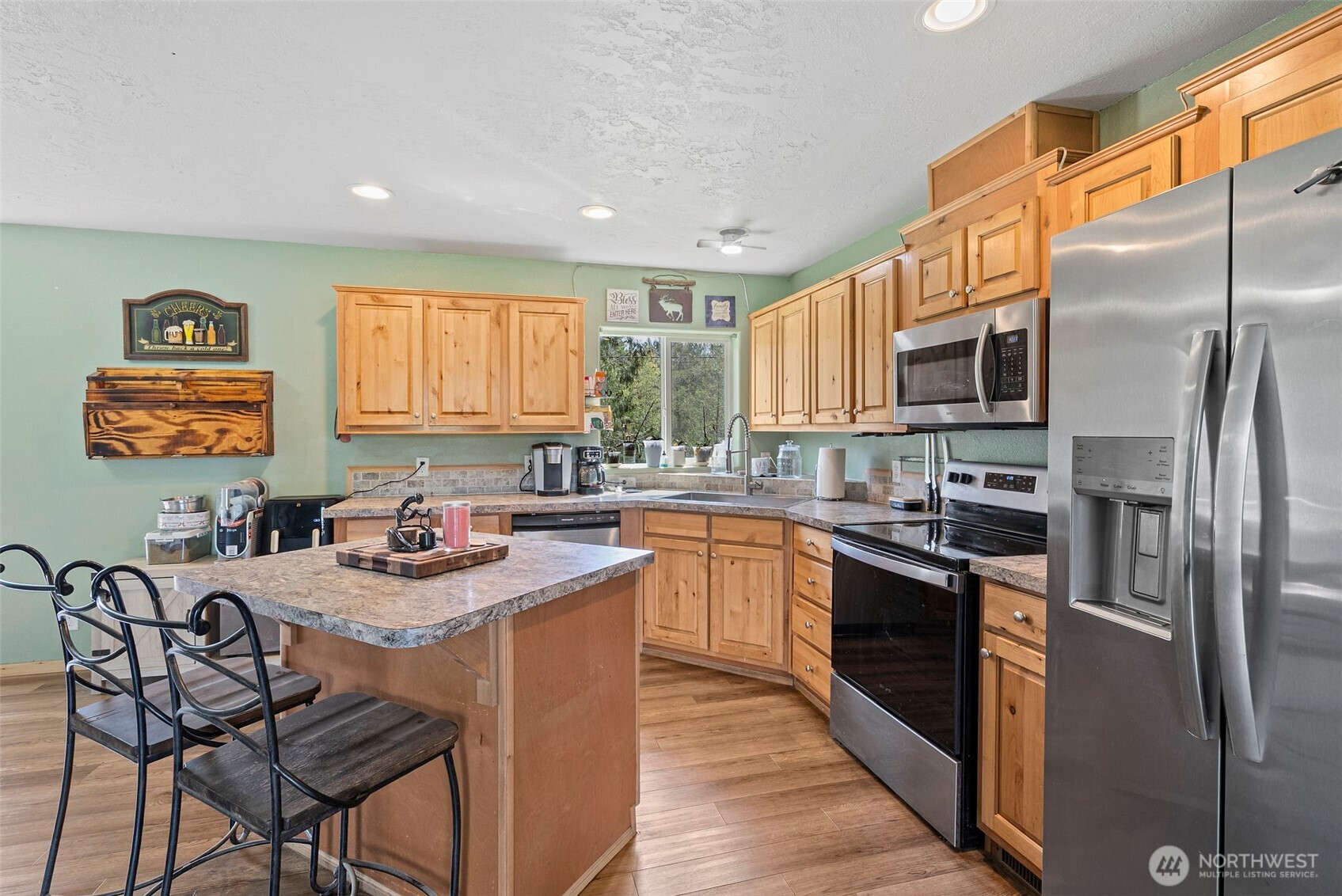 291 East Orchid Lane Grapeview, WA 98546 - Photo 8 of 37 a kitchen with stainless steel appliances granite countertop a stove a sink dishwasher a refrigerator and a dining table with wooden cabinet