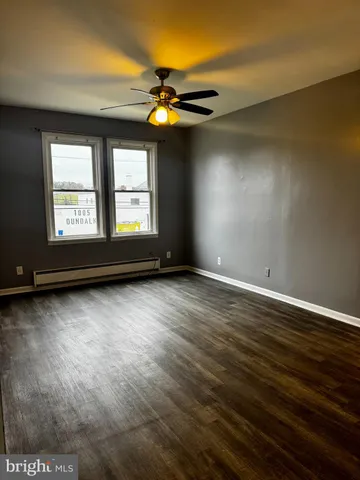 an empty room with wooden floor fan and windows