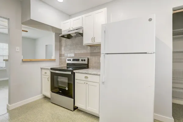 a white refrigerator freezer and a stove sitting inside of a kitchen