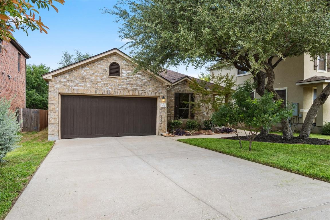 View of front of house with driveway, a garage, brick siding, and stucco siding
