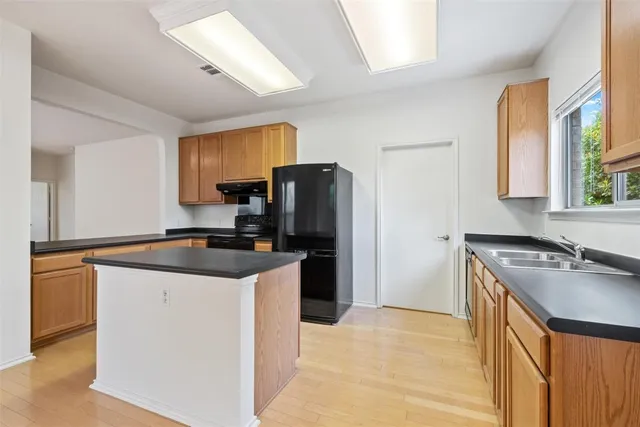 a kitchen with granite countertop a refrigerator a sink a stove and white cabinets
