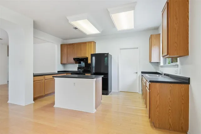 a kitchen with stainless steel appliances granite countertop a stove a sink a refrigerator and a cabinets