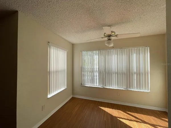 a view of an empty room with a window and wooden floor