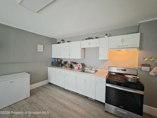 a kitchen with granite countertop white cabinets and stainless steel appliances